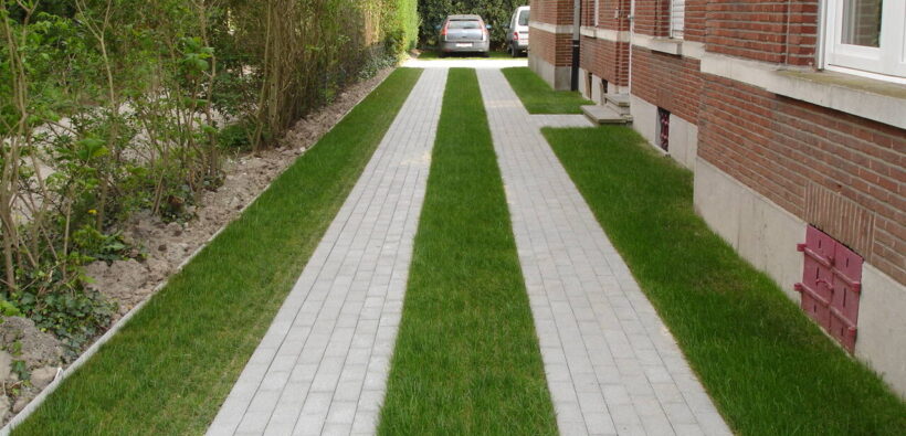Permeable driveway in Canada with grass strips between paver bands beside a brick home