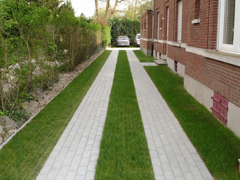 Grass strips between paver bands form a softscape alternative to a solid asphalt driveway